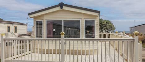 A mobile home with a covered porch and a fenced deck.