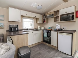 Una kitchenette compacta con microondas, tostadora, hervidor y un refrigerador pequeño.