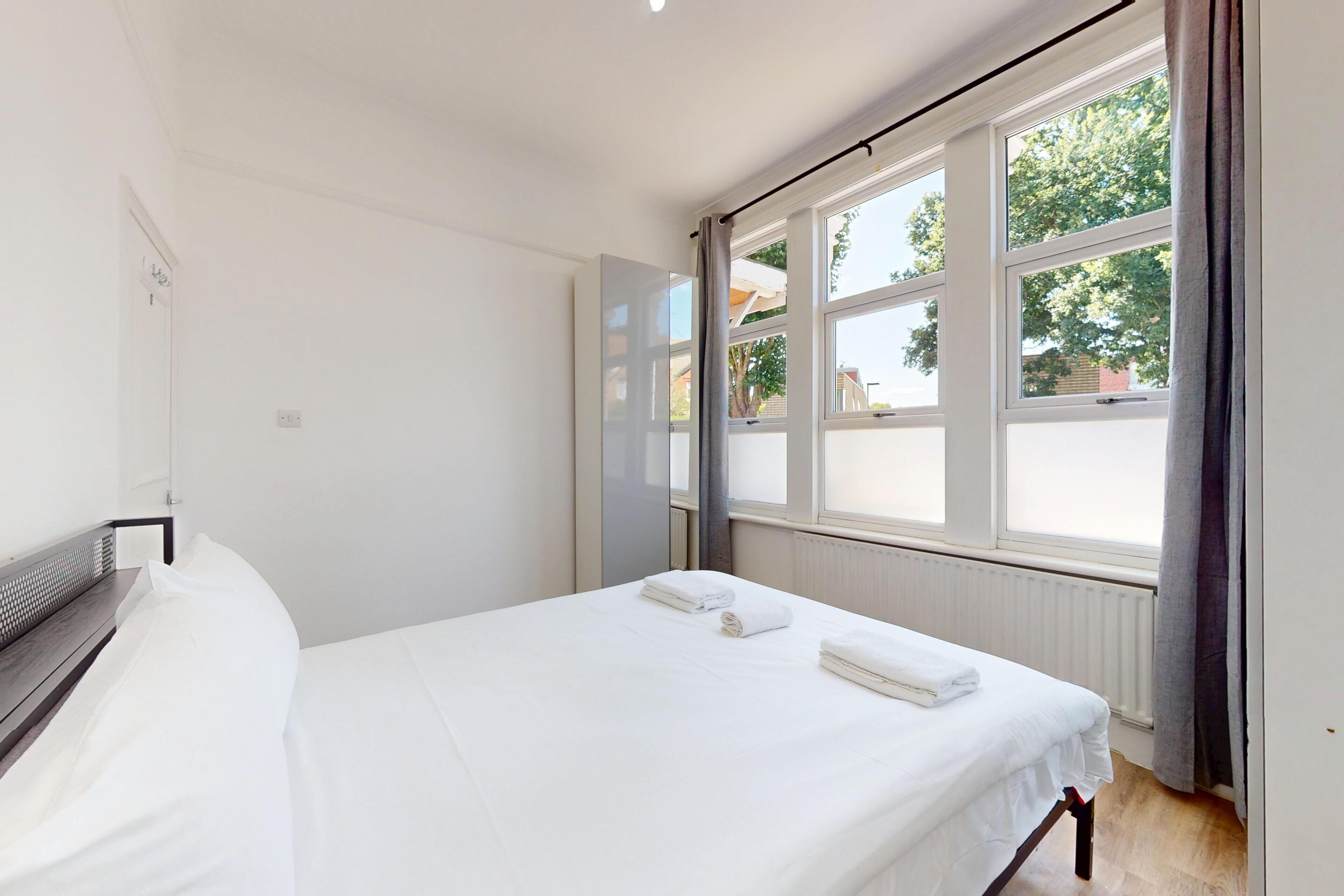 A bedroom with a bed, a window with curtains, and a radiator.