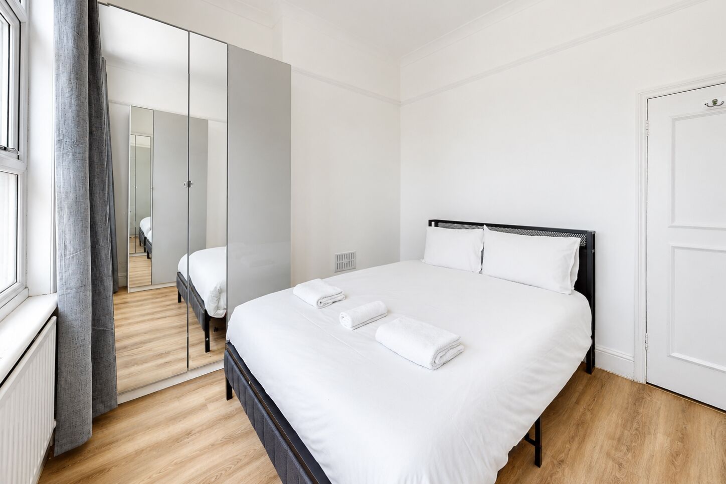 Une chambre d’hôtel avec un grand lit, un miroir et une vue sur une autre chambre.