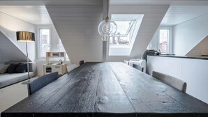 Eine moderne Loftwohnung mit großem Esstisch, einer Couch, einer Lampe und einer Küchenzeile.