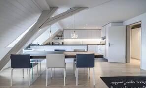 Une cuisine moderne dotée d’un îlot central, de meubles blancs et de luminaires suspendus.