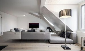 Ein modernes Wohnzimmer mit einem Ecksofa, einem Flachbildfernseher und einer Stehlampe.