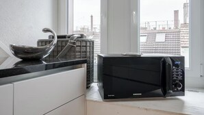 A modern kitchen with a black microwave oven, a stainless steel sink, and a window with a view of buildings.
