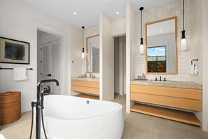 A modern bathroom with a freestanding bathtub, two sinks with mirrors, and a large window. - Makani Kai by Gather: Brand-New Luxury Home w/ Private Pool & Spa, AC, Chef’ (Koloa)