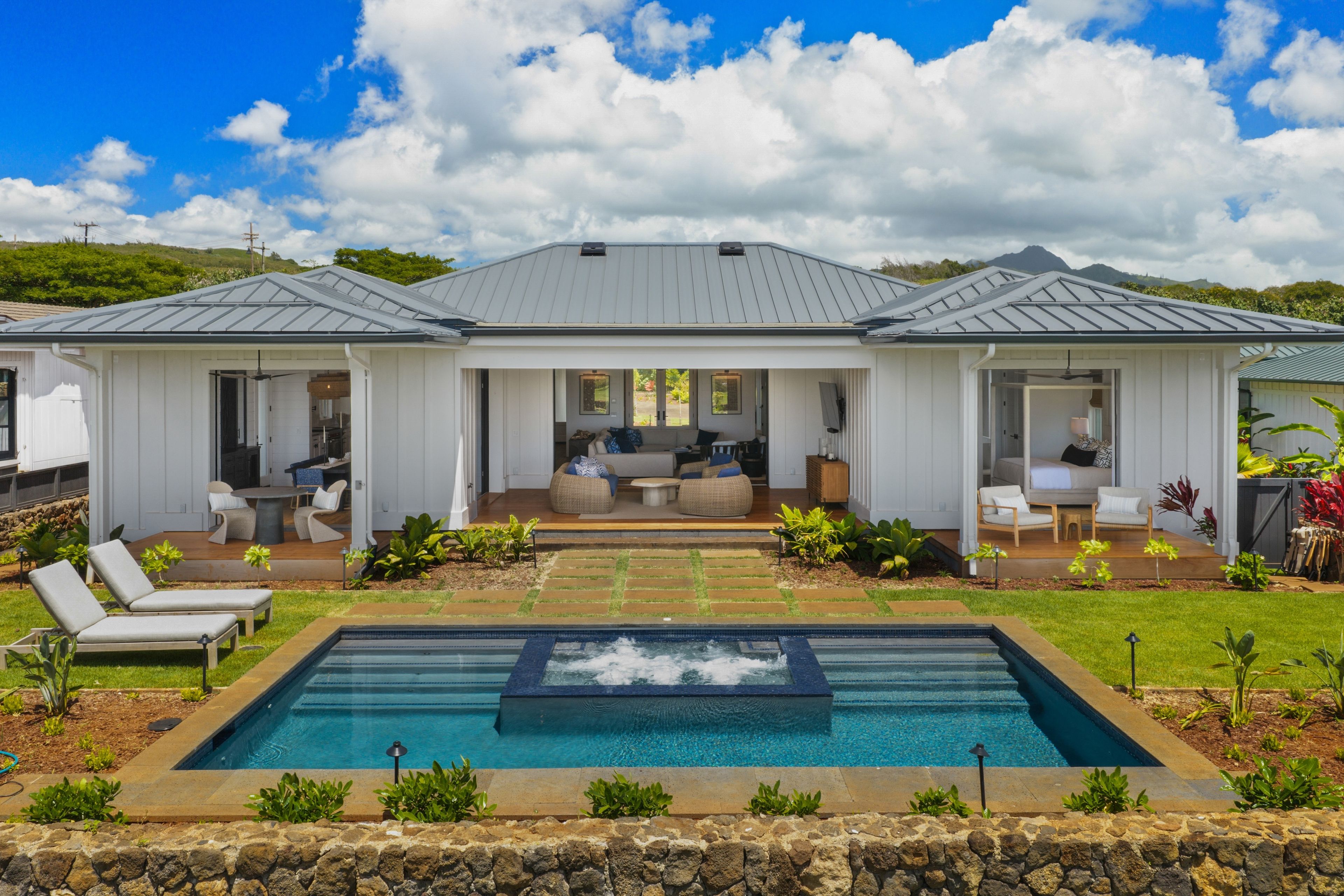 A modern house with a swimming pool, outdoor seating, and a view of the mountains.