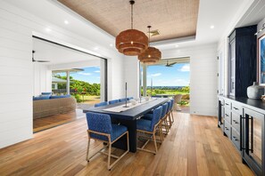 A modern kitchen with a large island, white cabinetry, and a view of the outdoors. - Makani Kai by Gather: Brand-New Luxury Home w/ Private Pool & Spa, AC, Chef’ (Koloa)