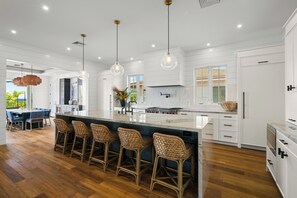 A spacious kitchen with a large island, bar stools, and pendant lighting. - Makani Kai by Gather: Brand-New Luxury Home w/ Private Pool & Spa, AC, Chef’ (Koloa)