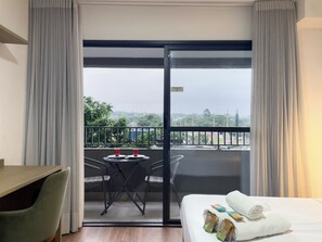 A hotel room with a bed, a desk, a chair, a small table with two cups, and a balcony with a view of the city. - Today Butantã  (São Paulo)