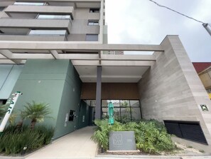 A modern building entrance with a green facade, a sign indicating 'TO DAY 1129', and a covered area with a wooden slatted roof. - Today Butantã  (São Paulo)