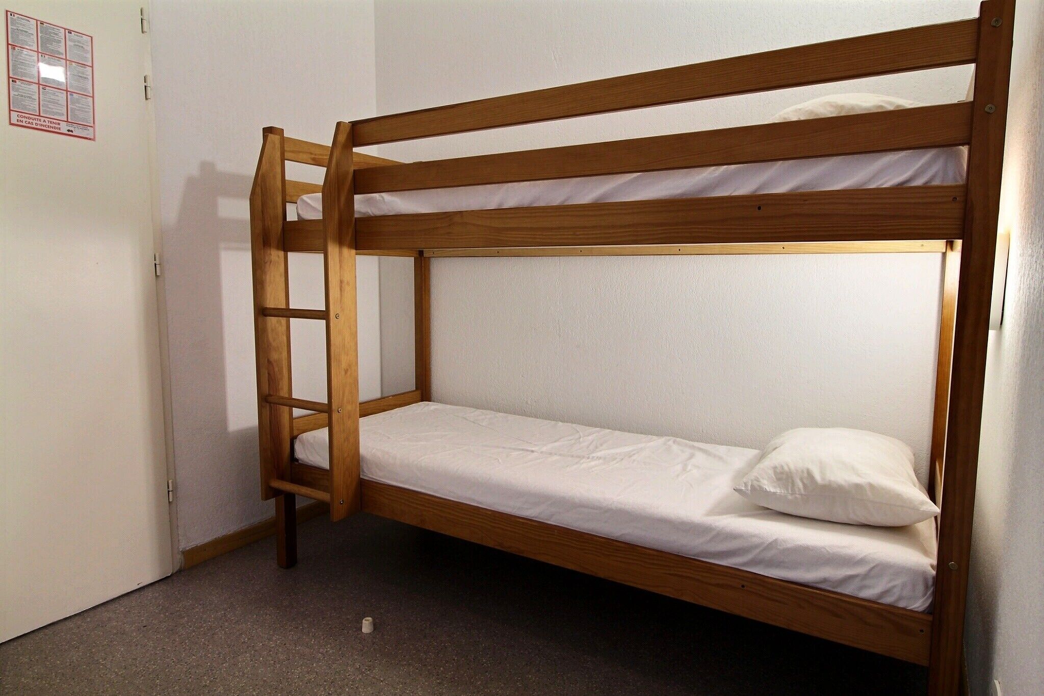Un letto a castello con struttura in legno e biancheria bianca.