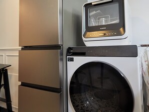 Eine kompakte Küche mit Edelstahl-Kühlschrank und integriertem Waschmaschinenanschluss.