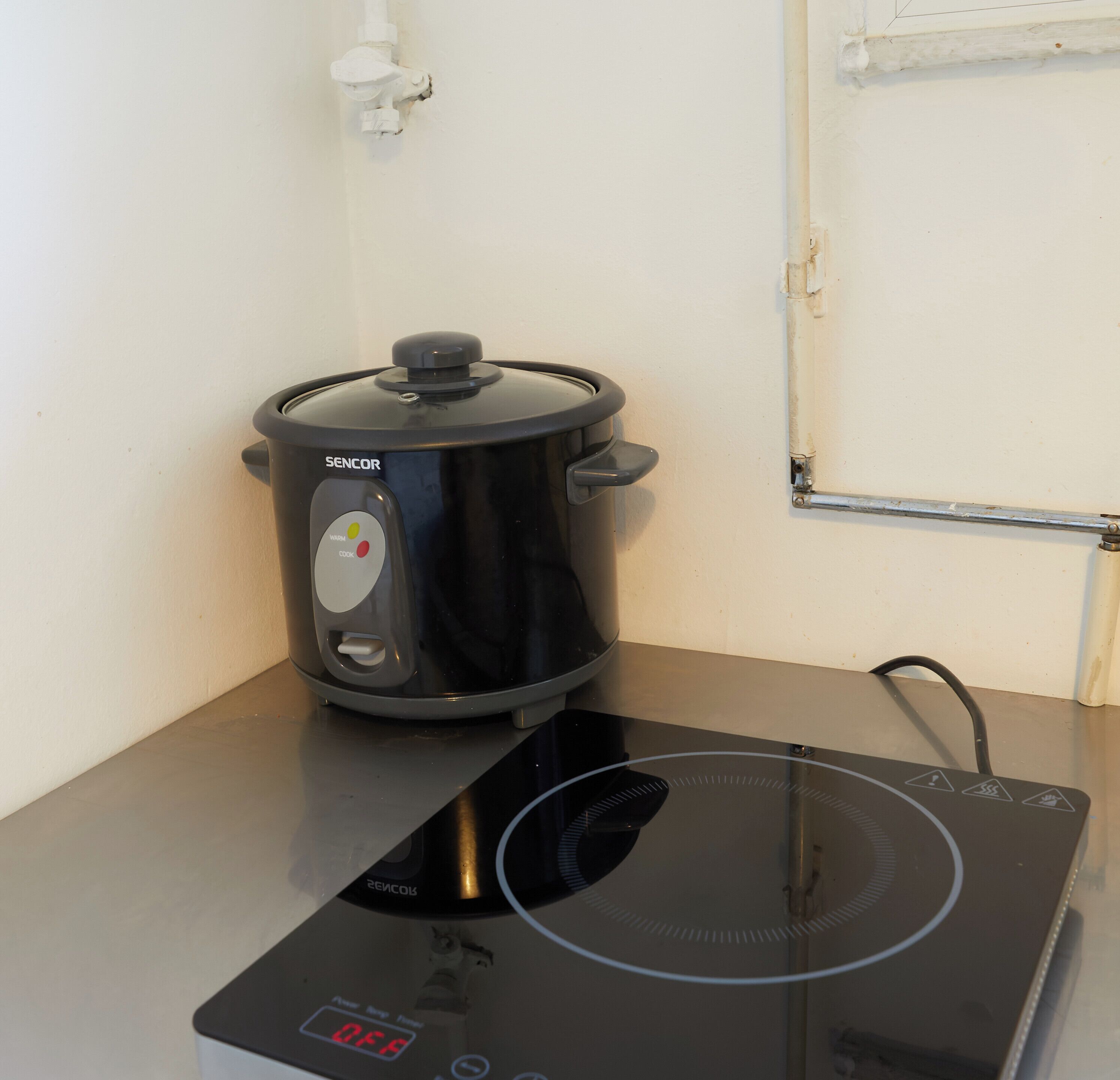 Een zwarte elektrische kookplaat met een digitaal display en een zwarte kookpan erboven.