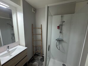 A bathroom with a white sink, mirror, shower, and a wooden ladder. - Apartment in the heart of Ouistreham beach (Ouistreham)