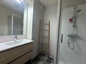 Ein Badezimmer mit Waschbecken, Spiegel und Dusche.