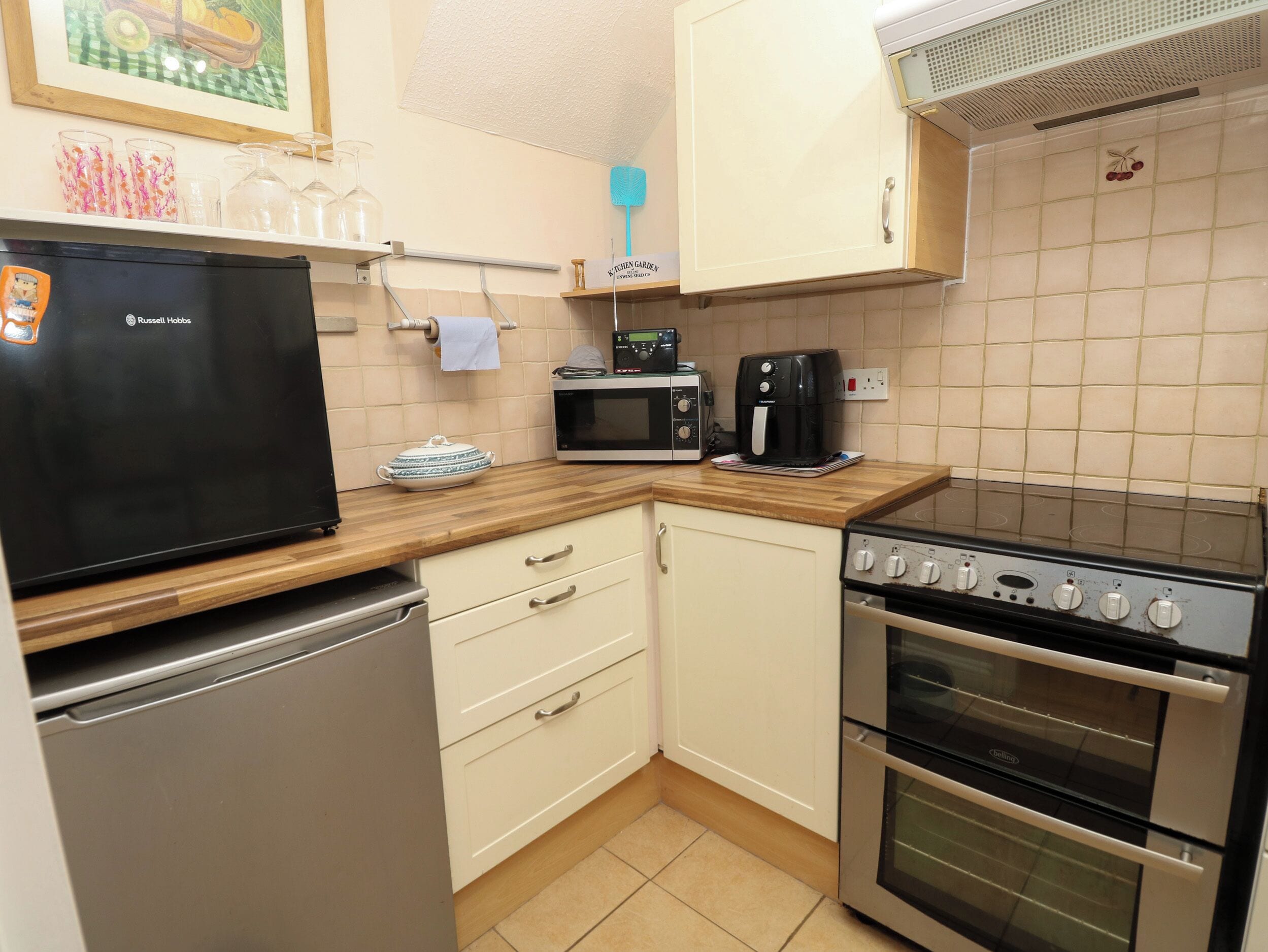A compact kitchen with a refrigerator, microwave, coffee maker, and double oven.
