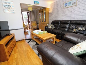 A living room with a leather sofa, wooden coffee table, and a television on a wooden stand. - 73 Pennywell Gardens (New Milton)