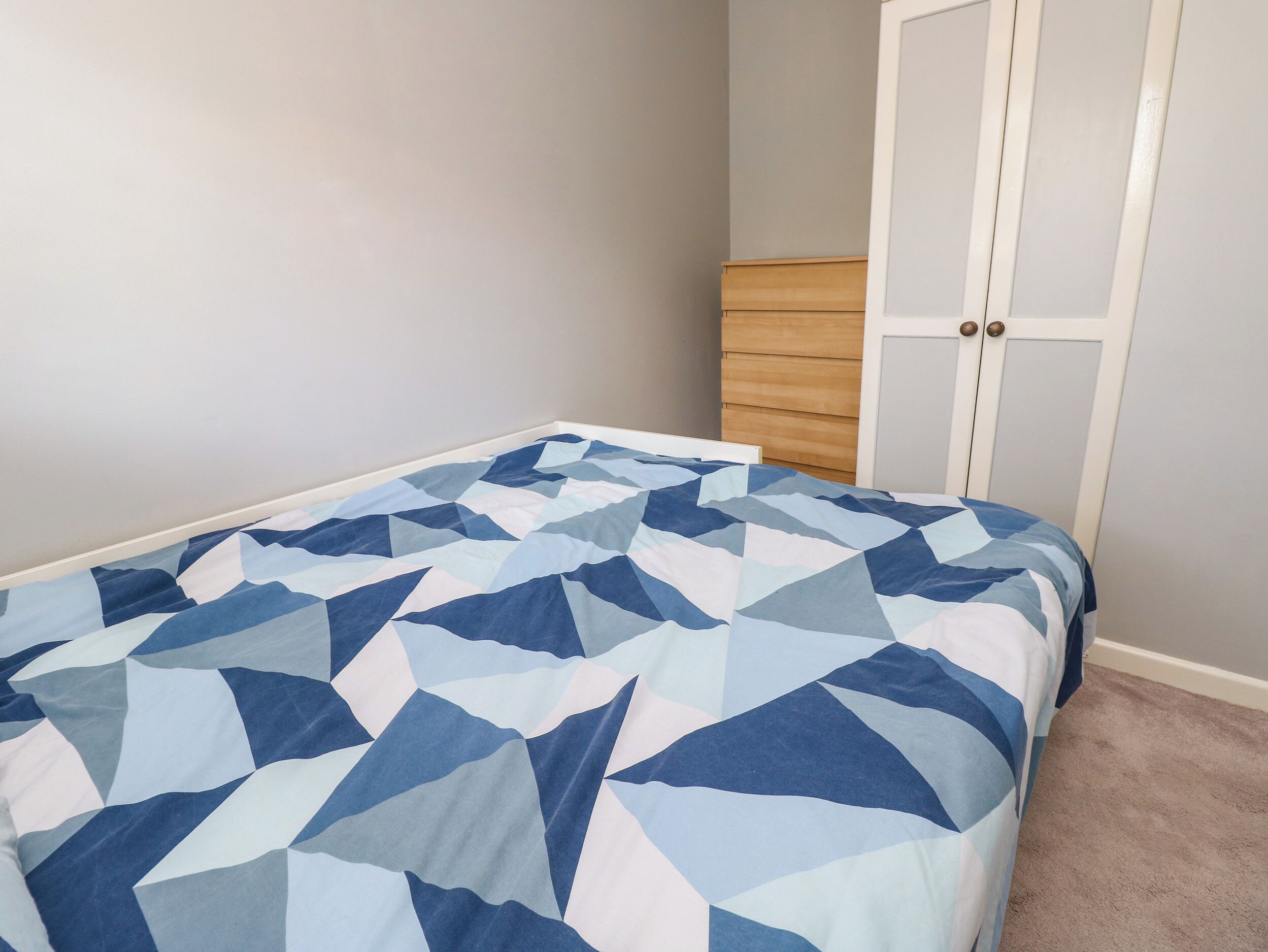 A bedroom with a bed, a dresser, and a wardrobe.
