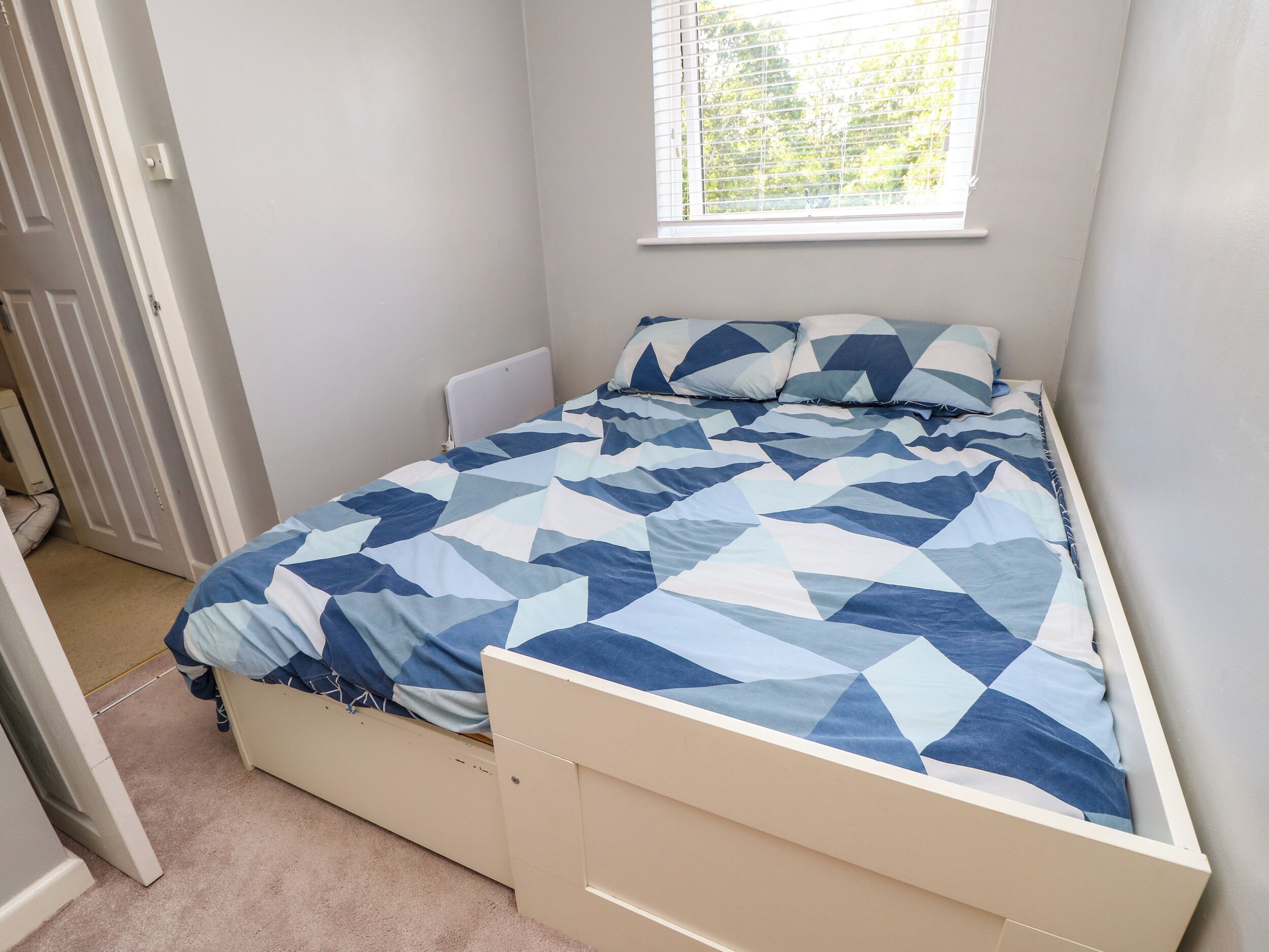 A bedroom with a bed, a window, and a radiator.