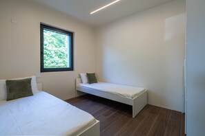 Ein Schlafzimmer mit zwei Betten, einem Fenster und einer weißen Wand.