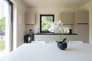 A modern kitchen with a white table, a potted orchid, and a window with a view of greenery. - A bright and welcoming 50-square-meter apartment, perfect for six people, located on the ground floor of a newly built building.The property is situated in an extremely quiet area and enjoys a strategic location, allowing you to easily visit Valeggio sul (Venturelli-Fenili)