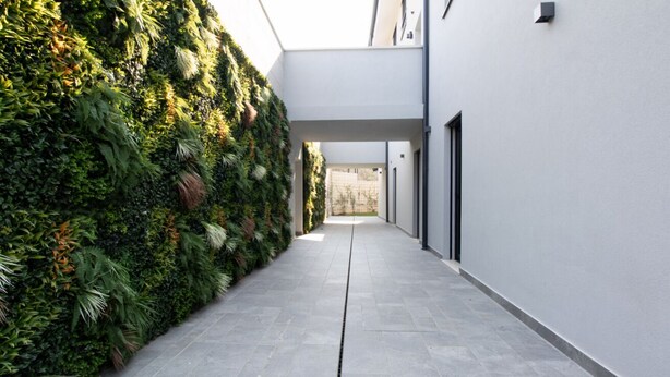 Un pasillo con un muro de jardín vertical y suelo de baldosas.