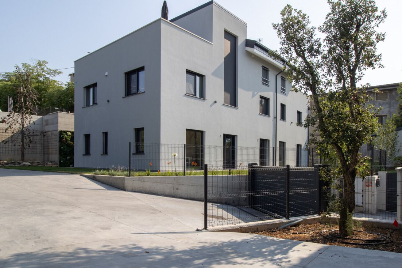 Un immeuble moderne à plusieurs étages, doté d’un toit plat, de fenêtres rectangulaires et d’une entrée fermée par un portail.