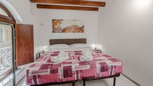 A bedroom with a bed, a wooden ceiling, a painting on the wall, and a window with a view. - A cozy 48 sqm apartment, ideal for up to 3 people, located on the ground floor of a building (accessible via one step).The property enjoys a strategic location, just 700 meters from Porta Nuova station and only 500 meters from the Marconi metro stop.It (Turin)