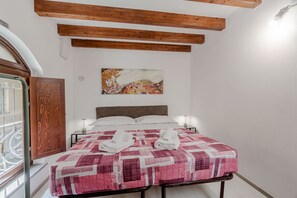 A bedroom with a bed, a wooden ceiling, a painting on the wall, and a window with a view. - A cozy 48 sqm apartment, ideal for up to 3 people, located on the ground floor of a building (accessible via one step).The property enjoys a strategic location, just 700 meters from Porta Nuova station and only 500 meters from the Marconi metro stop.It (Turin)