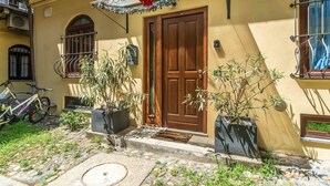 A yellow building with a wooden door, potted plants, a bicycle, and a stone pathway. - A cozy 48 sqm apartment, ideal for up to 3 people, located on the ground floor of a building (accessible via one step).The property enjoys a strategic location, just 700 meters from Porta Nuova station and only 500 meters from the Marconi metro stop.It (Turin)
