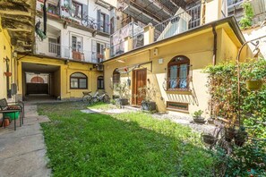 A courtyard with a yellow building, a wooden door, and a bicycle. - A cozy 48 sqm apartment, ideal for up to 3 people, located on the ground floor of a building (accessible via one step).The property enjoys a strategic location, just 700 meters from Porta Nuova station and only 500 meters from the Marconi metro stop.It (Turin)