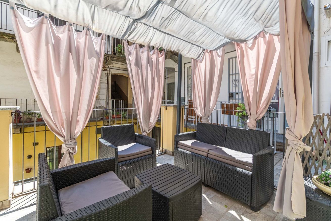 An outdoor seating area with wicker furniture and a covered patio.