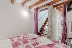 A bedroom with a bed, a stone wall, a wooden staircase, and a bathroom visible through an open door. - A cozy 48 sqm apartment, ideal for up to 3 people, located on the ground floor of a building (accessible via one step).The property enjoys a strategic location, just 700 meters from Porta Nuova station and only 500 meters from the Marconi metro stop.It (Turin)