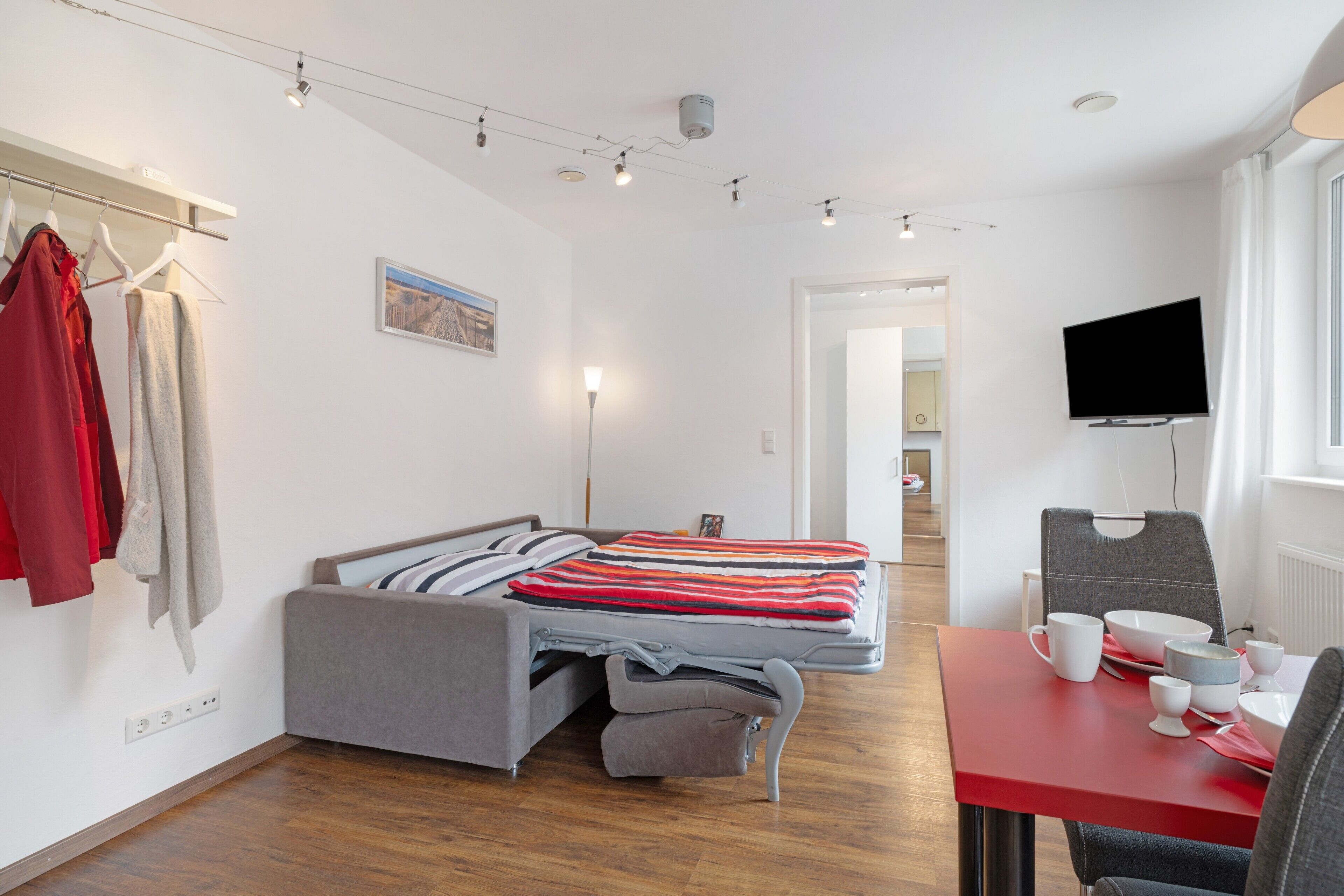 A modern bedroom with a bed, bedside table, and a TV mounted on the wall.