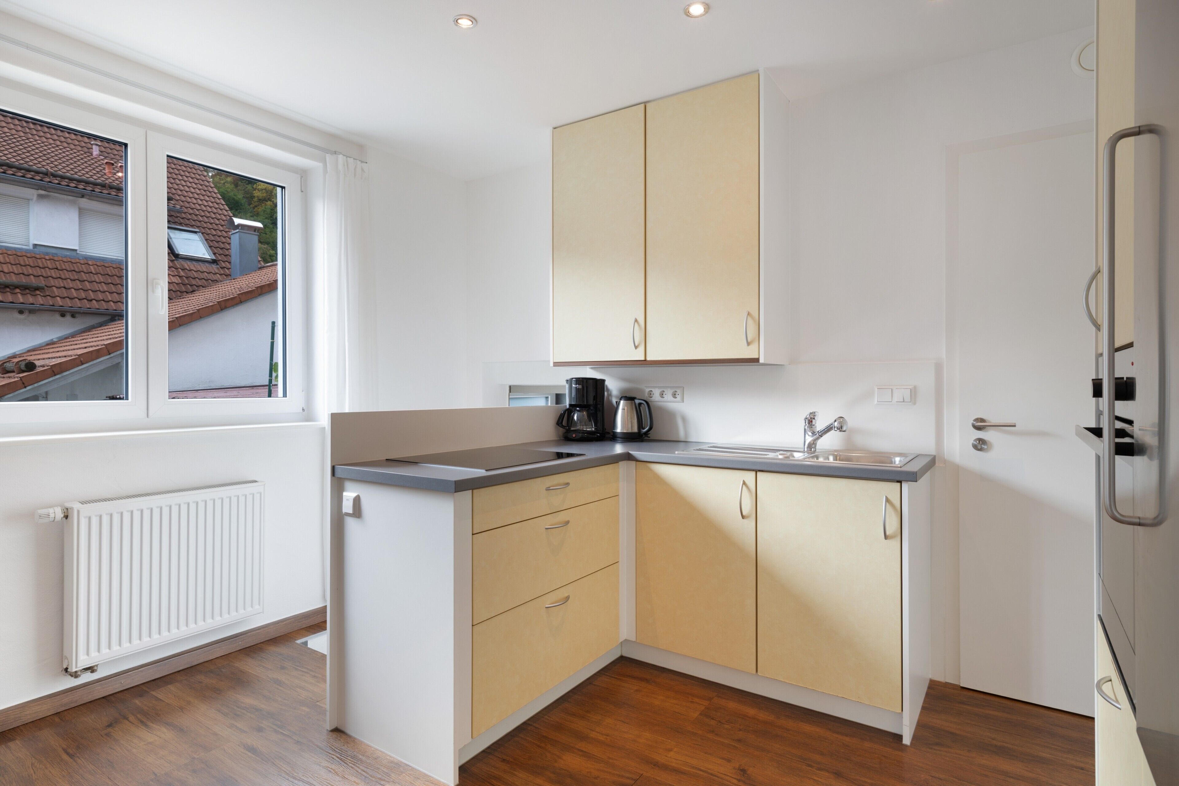 A compact kitchen with a window, a radiator, and a sink.