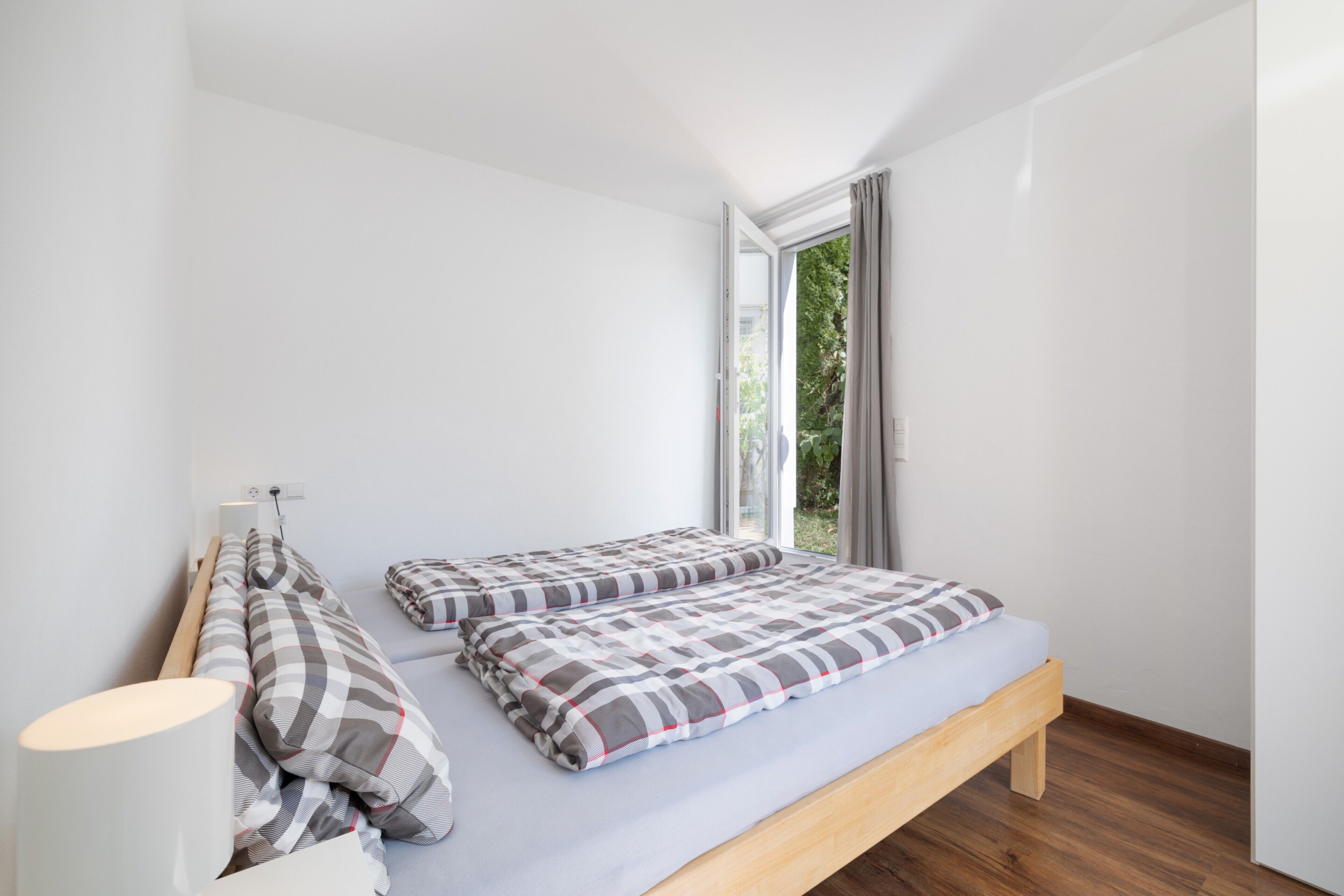 A bedroom with a bed, a bedside table, and a window with curtains.