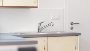 A kitchen with a stainless steel faucet, a double sink, and light-colored cabinets. - Gaiser Apartment, Urach Waterfall, Swabian Alb (Bad Urach)