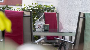 A glass-top table with a white lantern and a mug with text, surrounded by chairs with red and green towels. - Gaiser Apartment, Urach Waterfall, Swabian Alb (Bad Urach)
