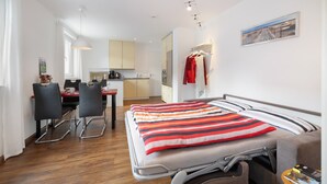 A modern hotel room with a bed, a desk, and a kitchenette. - Gaiser Apartment, Urach Waterfall, Swabian Alb (Bad Urach)