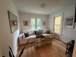 Ein Wohnzimmer mit einem weißen Sofa, einer Holzbank und gerahmten Bildern an den Wänden.