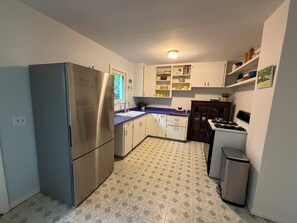 A compact kitchen with a refrigerator, sink, cabinets, and a stove. - Cozy 3-bedroom house in the heart of the east side of Madison (Madison)