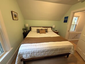 A bedroom with a bed, bedside tables, a window, and a door. - Cozy 3-bedroom house in the heart of the east side of Madison (Madison)