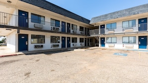 A two-story motel with a gravel parking area and a covered walkway.