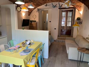 A cozy interior with a dining area, a sofa, and a staircase leading to another room. - Cozy vacation home in an old farmhouse on Lake Iseo (Sarnico)