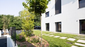 Un bâtiment moderne doté d’une pelouse bien entretenue, d’un arbre et d’une clôture en métal.