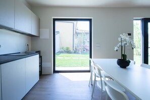 A modern kitchen with a sliding glass door leading to a garden. - GuestHost - Cozy Apartment with Parking (Venturelli-Fenili)
