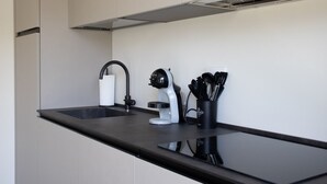 Une cuisine moderne avec un plan de travail noir, un évier blanc et une machine à café.