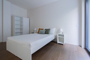A minimalist bedroom with a single bed, nightstands, a wardrobe, and a window. - GuestHost - Cozy Apartment with Parking (Venturelli-Fenili)