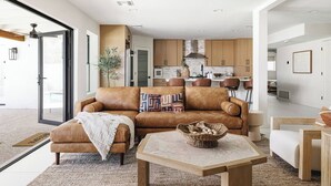 A modern living room with a leather sofa, a coffee table, and a kitchen in the background. - LUXE - SOTO Luxury House in Old Town Scottsdale (Scottsdale)