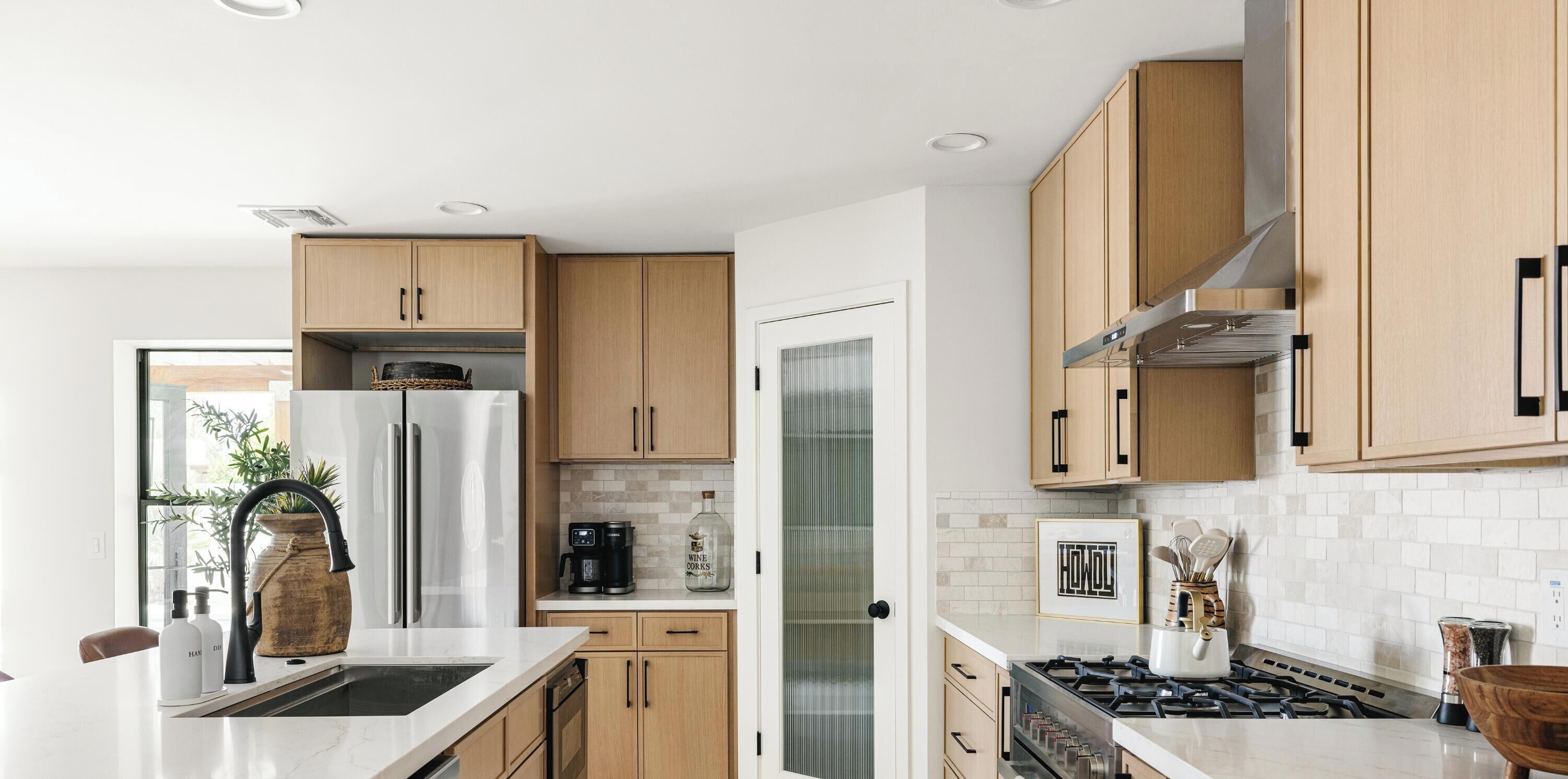 A modern kitchen with a stainless steel refrigerator, a coffee maker, and a stove.